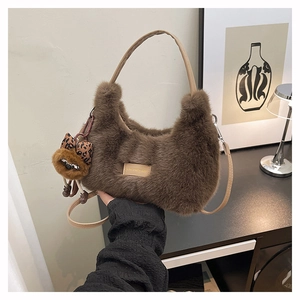Detail of coffee faux fur texture on a crescent bag with a decorative leopard bow charm