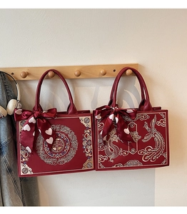 Detail of red bridal tote bags with golden dragon embroidery and silk ribbon decor