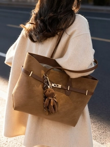 Chic brown suede tote bag with golden buckle and plush bear pendant on model shoulder