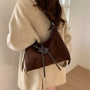 Detail of dark brown suede hobo bag featuring leather tassels and matte retro texture