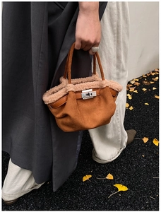 Close-up of caramel suede tote bag with cream shearling trim and silver metal twist lock