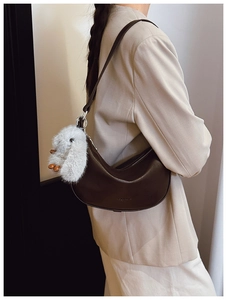Detail of a dark brown half-moon shoulder bag with a cute plush rabbit charm