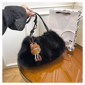 Detail of black fluffy faux fur tote bag with a whimsical plush figure pendant and thin straps