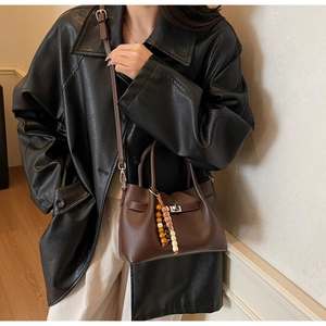 Détail d'un sac seau marron avec texture litchi et pampille de perles colorées