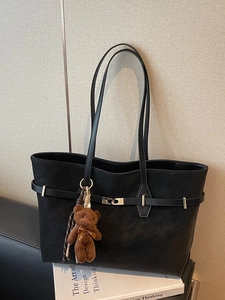 Minimalist black faux leather tote bag with shoulder straps and brown plush bear charm