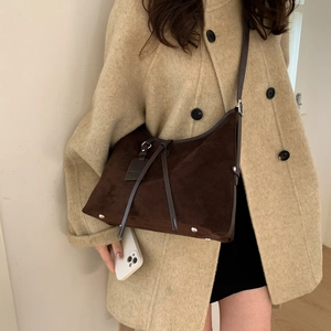 Detail view of large dark brown suede dumpling bag on a model wearing khaki coat