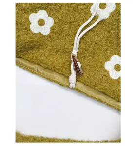 Detail of yellow plush tote bag showing horn button closure and white floral embroidery