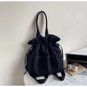 Detail showing the large capacity black bucket bag with dual front pockets and drawstring
