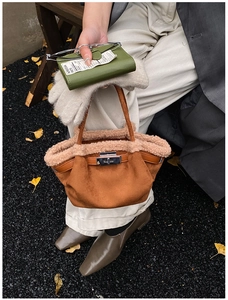 Close-up of brown suede bucket bag with beige plush trim and silver metallic clasp
