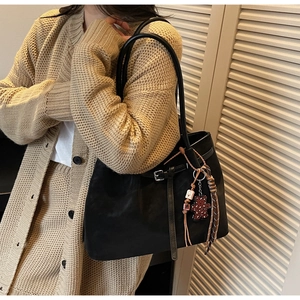 Detail of black tote bag with matte leather texture and leopard print bear charm