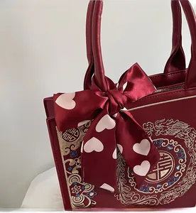 Detail of burgundy bridal handbag with golden dragon embroidery and silk bow handle