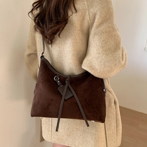 Detail of dark brown faux suede dumpling bag with slim strap and silver metal hardware