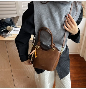 Close-up of brown faux leather bucket bag with retro wooden beads and knot handle