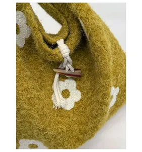 Detail of mustard yellow plush tote bag with white flower embroidery and horn button closure