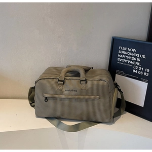 Detailansicht der grünen karierten Canvas-Reisetasche mit Tragegriffen und Schultergurt