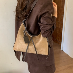 Detail view of camel suede hobo bag with vintage tassels and dark brown leather trim