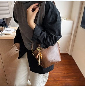 Close-up of a vintage brown leather bucket bag featuring a unique beaded charm detail