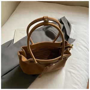 Close-up of brown pebbled faux leather tote bag with top zipper and inner fabric lining