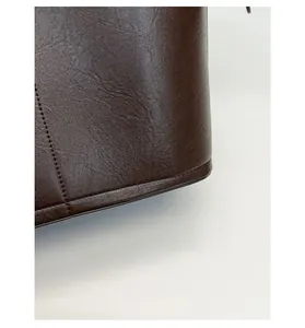 Détail de la texture cuir marron foncé avec coutures nettes sur ce sac seau