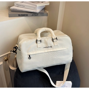 Detail einer cremefarbenen Reisetasche mit Weilaibag-Logo auf blauem Hocker im Zimmer
