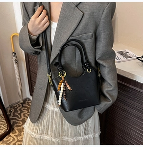 Detail view of black lychee texture bucket bag with vintage beaded tassel ornament