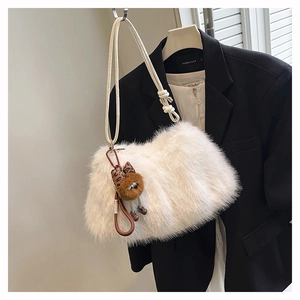 Detail of white plush shoulder bag featuring a cute doll pendant on a black blazer