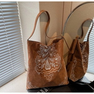 Nahaufnahme der braunen Wildleder-Tragetasche mit weißer floraler Stickerei im Boho-Stil