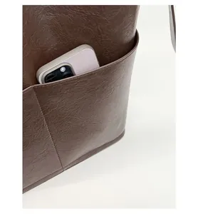 Détail d'un sac seau en cuir grainé marron foncé montrant la poche latérale pratique