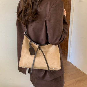 Detail of camel suede hobo bag with dark brown strap and metal protective feet on base