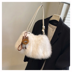Detail of soft white faux fur shoulder bag with a cute brown plush puppy charm