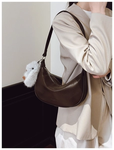 Detail of dark brown hobo shoulder bag featuring a metal zipper and plush rabbit charm