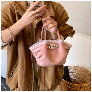 Detailed close-up of pink suede bucket bag with faux fur trim and silver metal twist lock