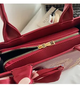 Detail of smooth gold zipper on a red embroidered tote bag with a decorative silk scarf