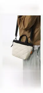 Dettaglio borsa a secchiello trapuntata bianco panna con coulisse nera ed etichetta arancione