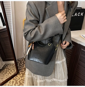 Detailed view of black bucket bag with vintage wooden beads and sleek leather texture