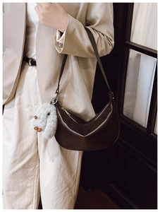 Detail of dark brown leather hobo bag with silver zipper and plush bunny charm