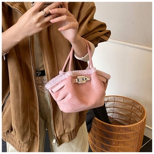 Detail of pink faux suede tote bag with plush fur trim and twist-lock closure design