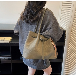 Detail of army green vintage tote bag with decorative straps and ethnic tassel pendant