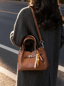 Sac seau en cuir marron avec breloque en perles photographié à la lumière du soleil
