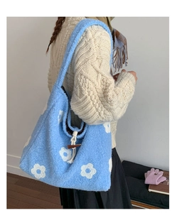 Detail of blue plush tote bag with white flower embroidery and toggle button closure