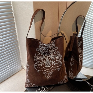Detail einer braunen Vintage-Wildleder-Tote-Bag mit weißer Blumenstickerei und Riemen