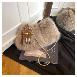 Detail of taupe faux fur shoulder bag texture with light strap and plush doll pendant