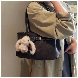 Close-up of a textured leather tote bag featuring a cute white plush bunny charm