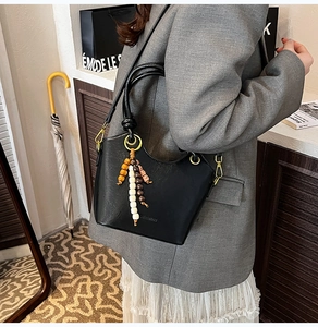 Detail of black matte leather bucket bag with boho beaded tassels and gold hardware