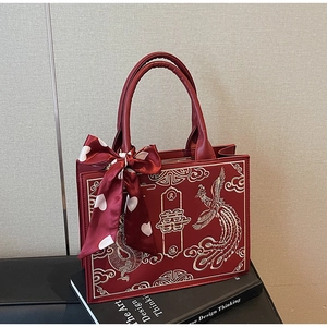 Detail of red bridal handbag with golden dragon phoenix embroidery and heart print silk scarf