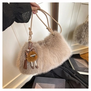 Detailed macro view of soft faux fur texture and cute plush owl pendant on a hobo bag