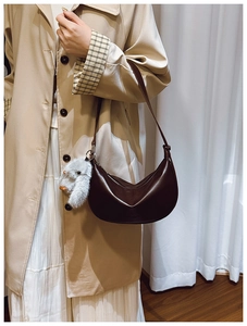 Chic dark brown crescent hobo bag with a cute plush bunny charm shown on a model