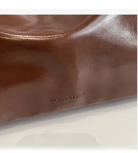 Macro shot of dark caramel brown leather texture and SOLAR & MISS embossed logo detail