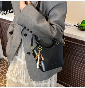Detail of black leather bucket bag featuring colorful beaded fringe and gold hardware