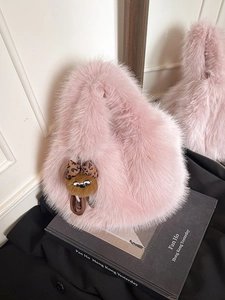 Secchiello in ecopelliccia rosa con ciondolo di peluche su libro fotografico invernale